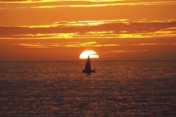 Sailboat silhouetted against a blazing Pacific sunset