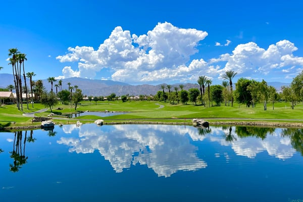 Lush golf course with palm trees and mountain reflections